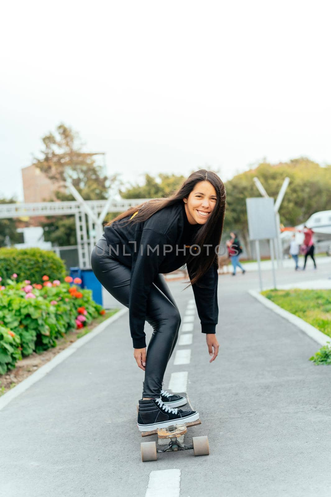 Young girl on longboard smiling. Outdoors, lifestyle. by Peruphotoart