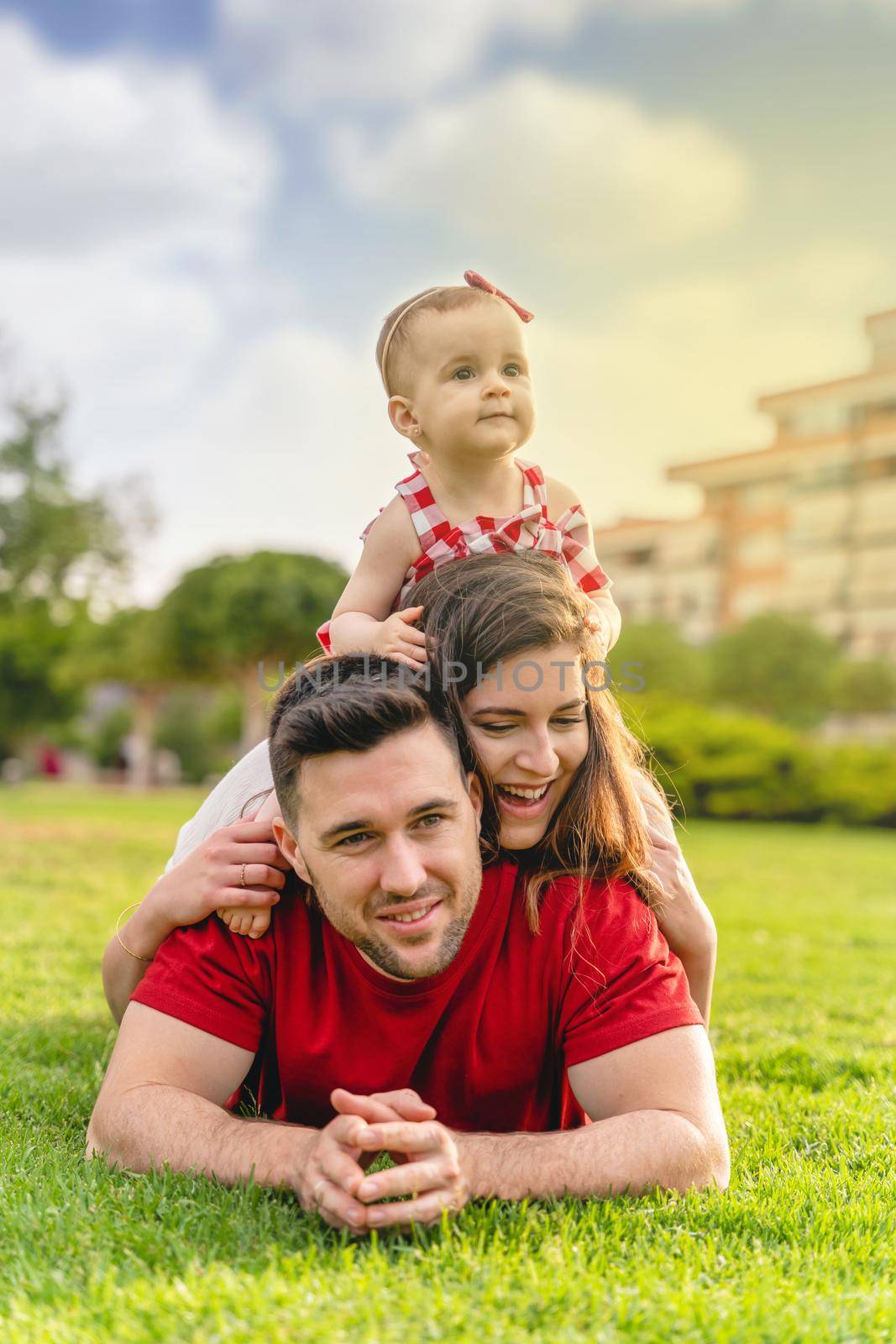 Portrait of happy young Family lying on grass by Mareno