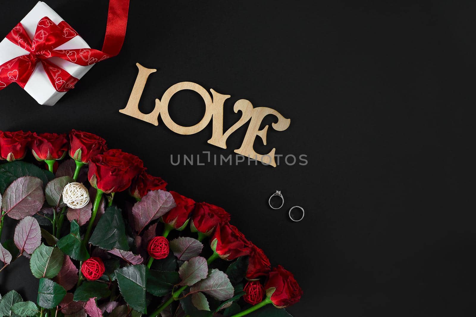 Red roses, ring and gift box on black background by nazarovsergey