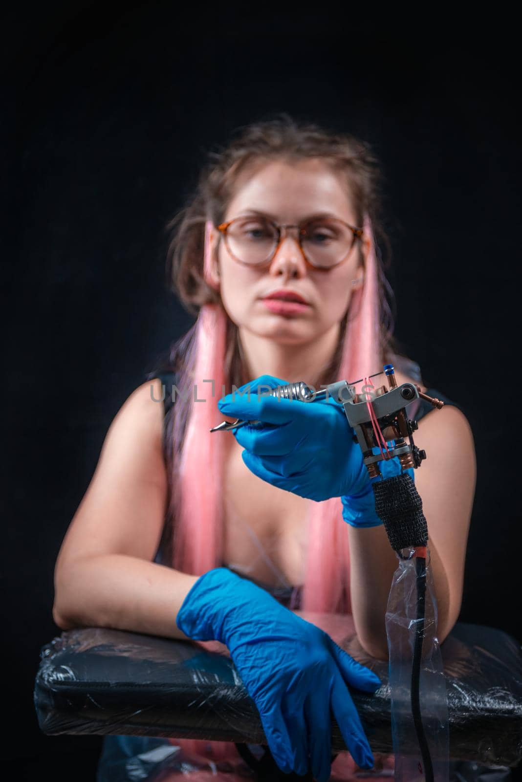 Tattooer with a tattoo-machine in tatoo salon.