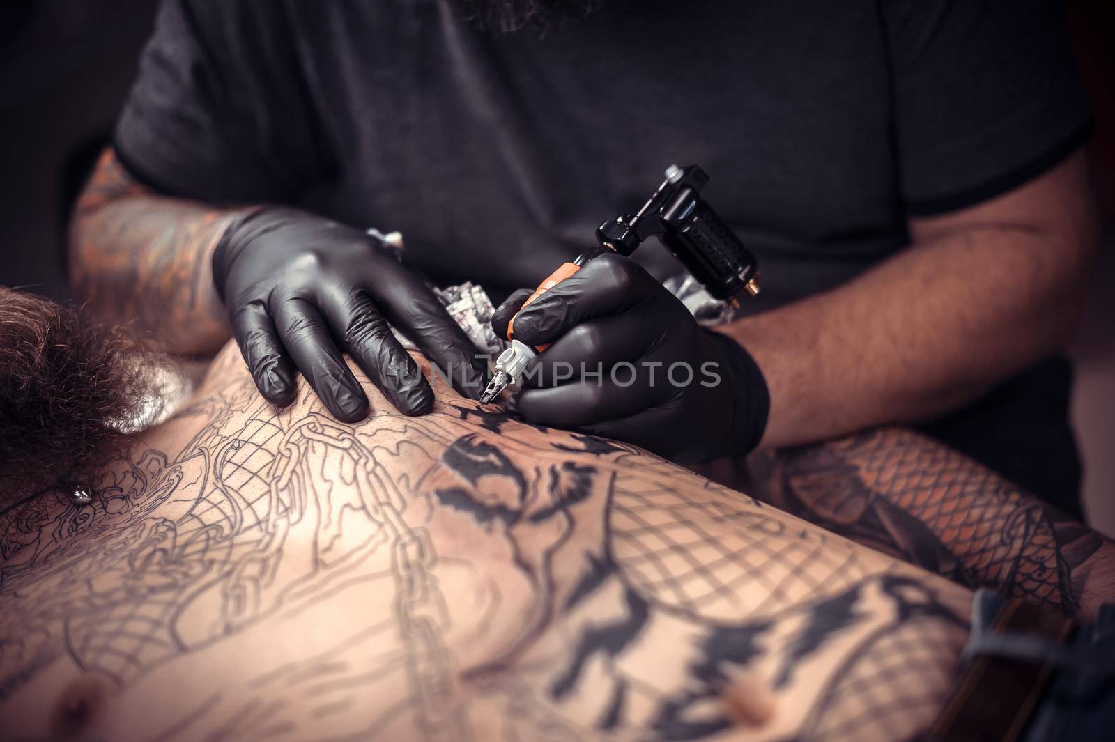 Professional tattooist at work in tattoo studio./Tattoo artist showing process of making a tattoo in a workshop studio.