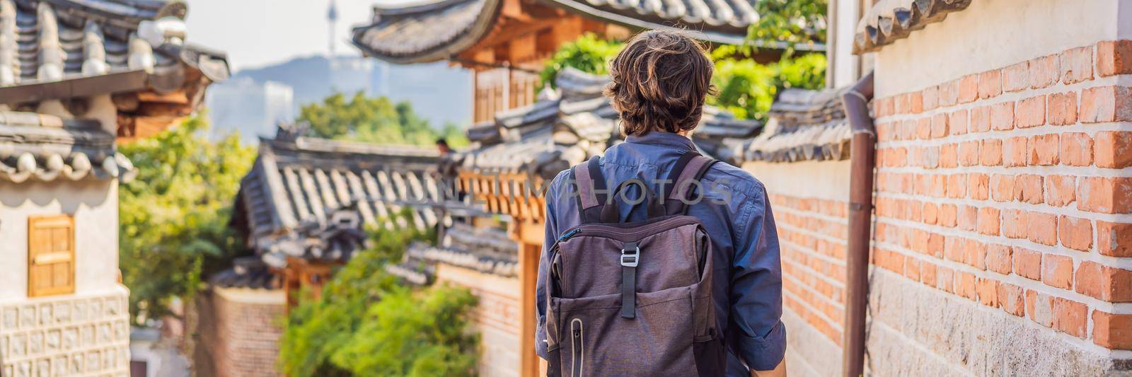 Young man tourist in Bukchon Hanok Village is one of the famous place for Korean traditional houses have been preserved. Travel to Korea Concept BANNER, LONG FORMAT by galitskaya