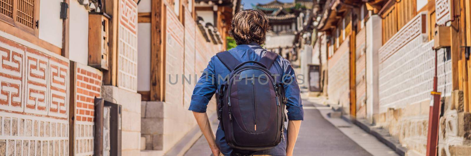 Young man tourist in Bukchon Hanok Village is one of the famous place for Korean traditional houses have been preserved. Travel to Korea Concept BANNER, LONG FORMAT by galitskaya