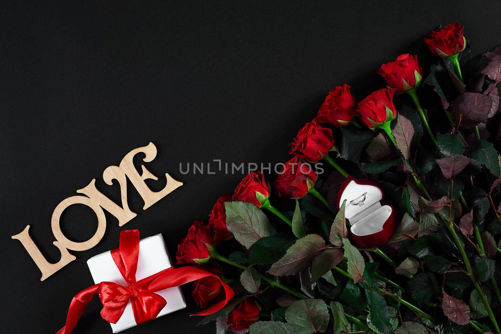 Red roses, ring and gift box on black background by nazarovsergey
