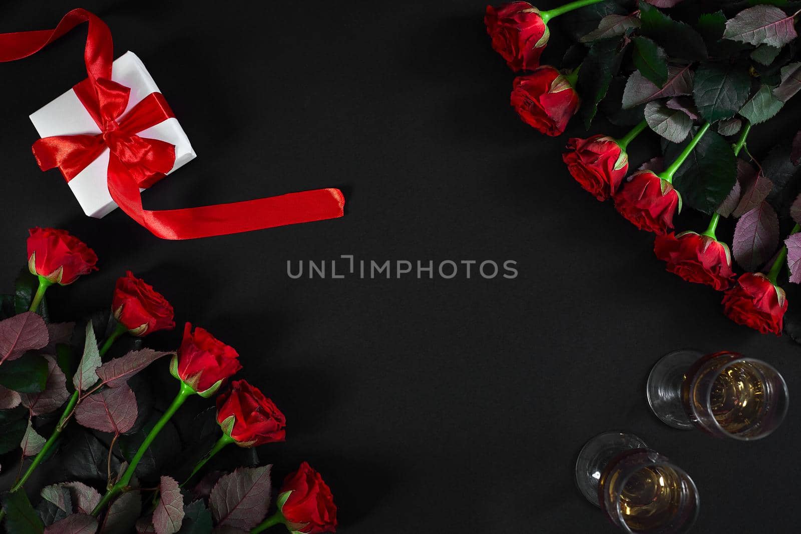 Red roses, ring and gift box on black background. Top view. Flat lay. Copy space. Still life