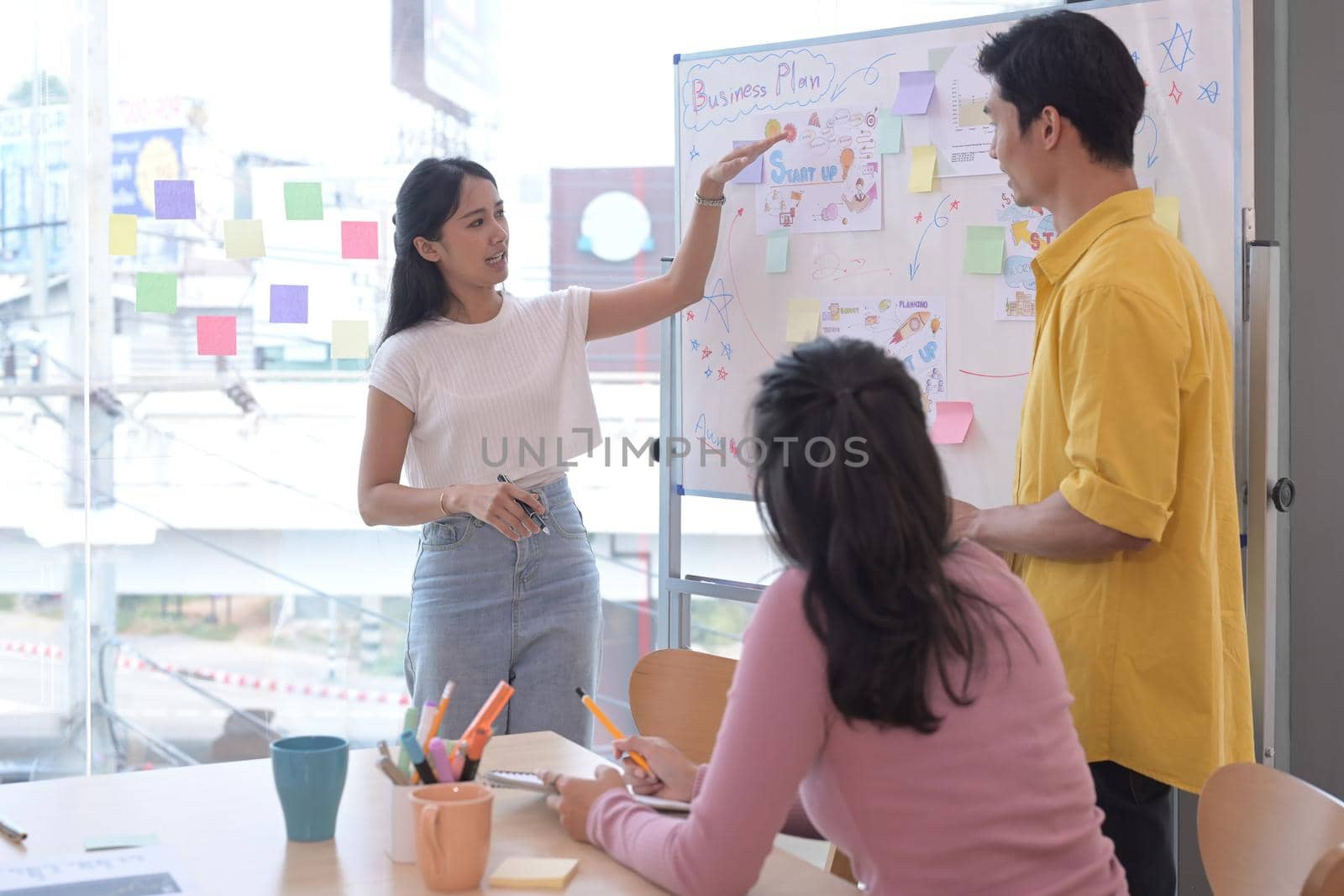Attractive businesswoman giving presentation to her business colleagues in the conference room. by prathanchorruangsak