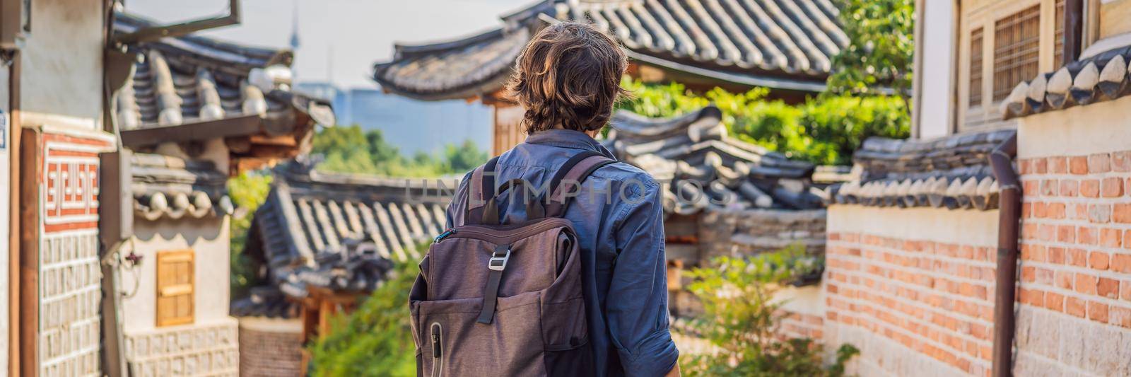 Young man tourist in Bukchon Hanok Village is one of the famous place for Korean traditional houses have been preserved. Travel to Korea Concept BANNER, LONG FORMAT by galitskaya
