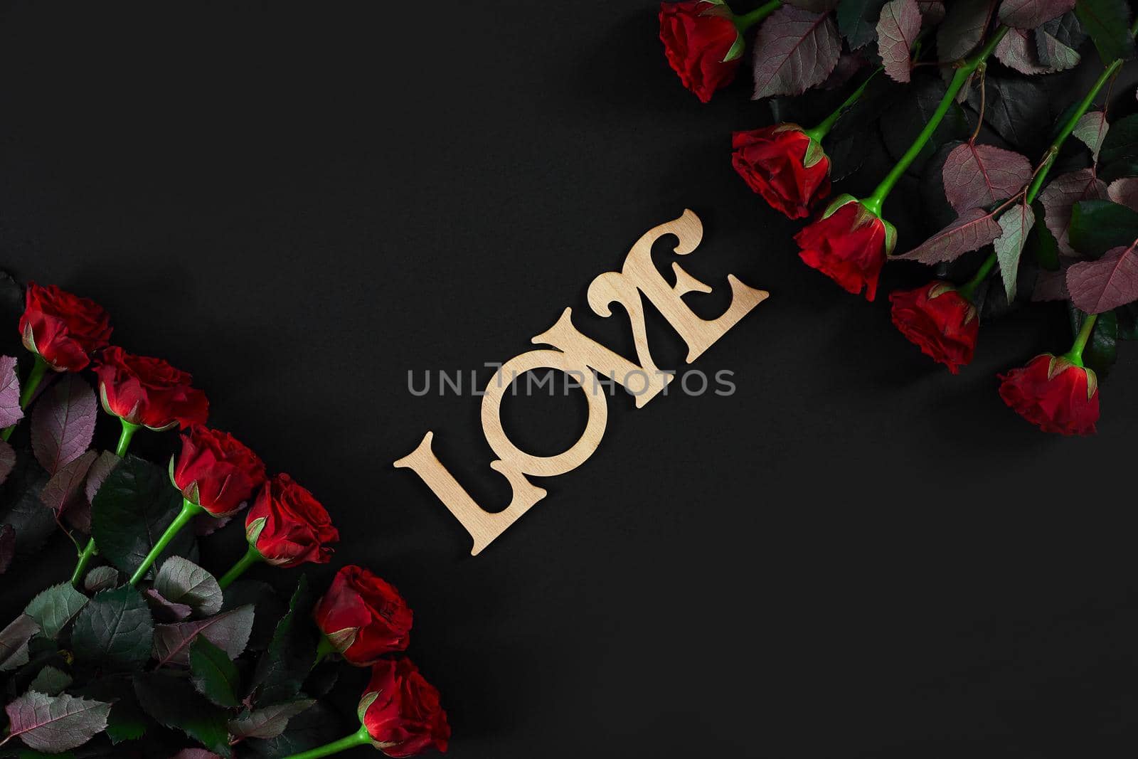 Red roses flowers with wooden word LOVE on black background with by nazarovsergey