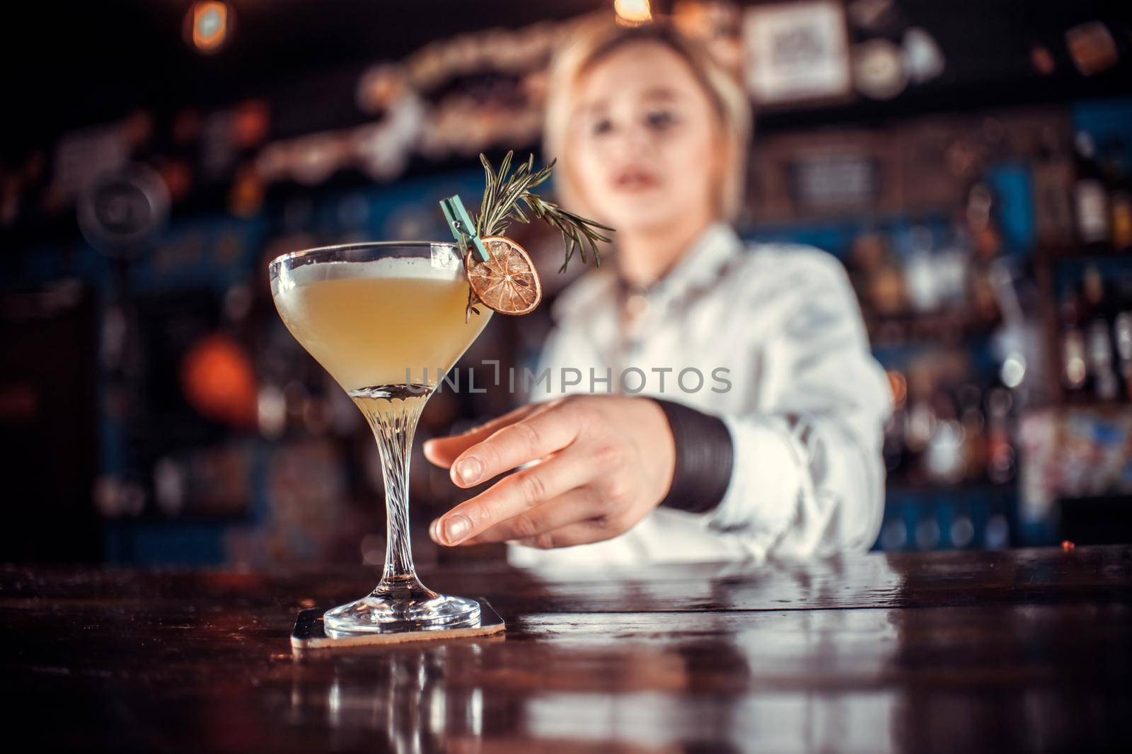 Experienced woman barman formulates a cocktail at the bar counter