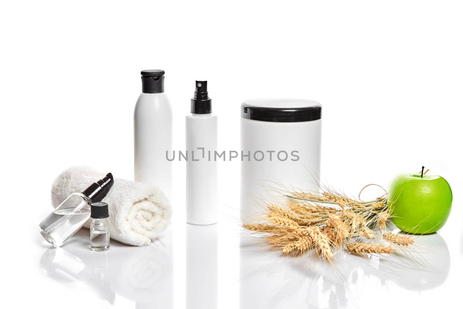 Spa cosmetics, jar of cream, oil with wheat, white cosmetic bottles with apple and wheat towel, candle, soap isolated on white. Without label. The concept for advertising cosmetics. Still life. Copy space