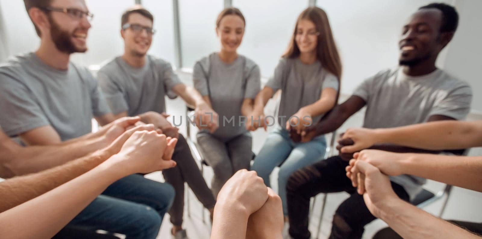 close up. a group of diverse young people holding hands by asdf