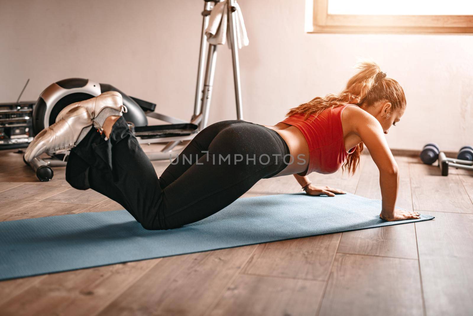 Beautiful young woman doing push-up at her home.