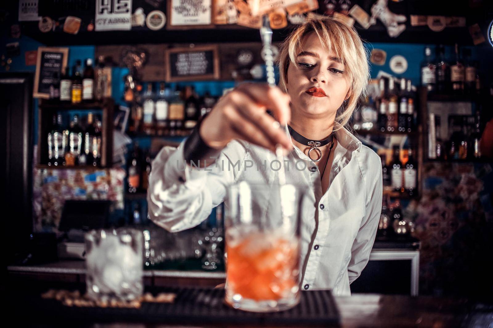 Girl bartender mixes a cocktail in the taproom by Proff