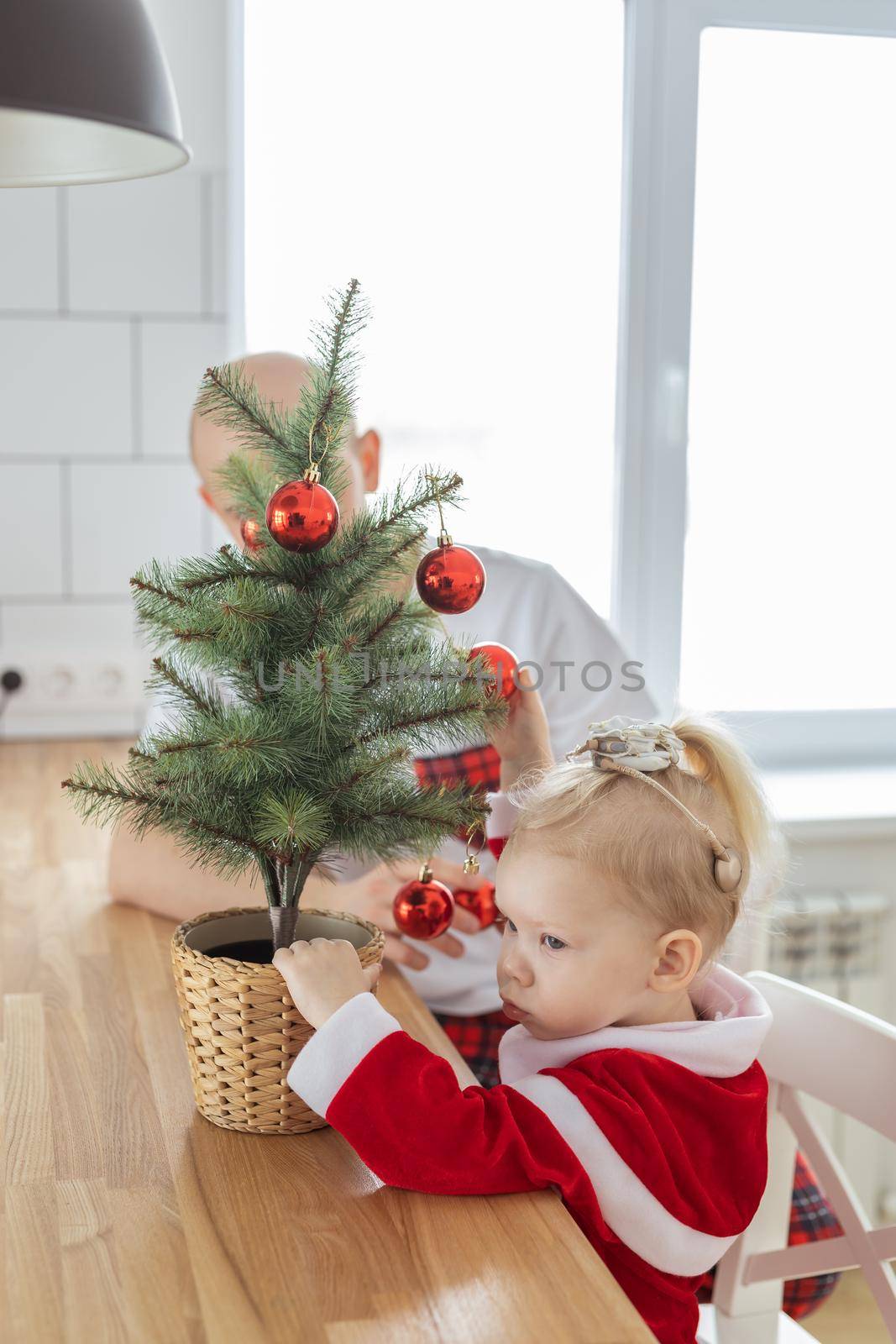 Child with cochlear implant hearing aid having fun with father and small christmas tree - diversity and deafness treatment and medical innovative technologies by Satura86