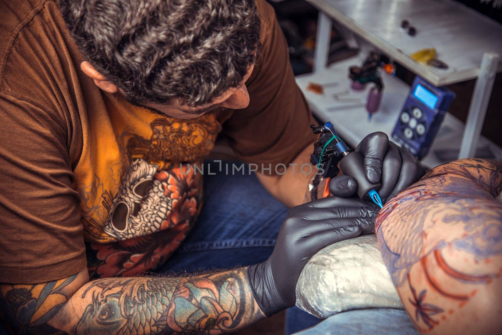 Tattoo master showing process of making a tattoo in tattoo parlor by Proff