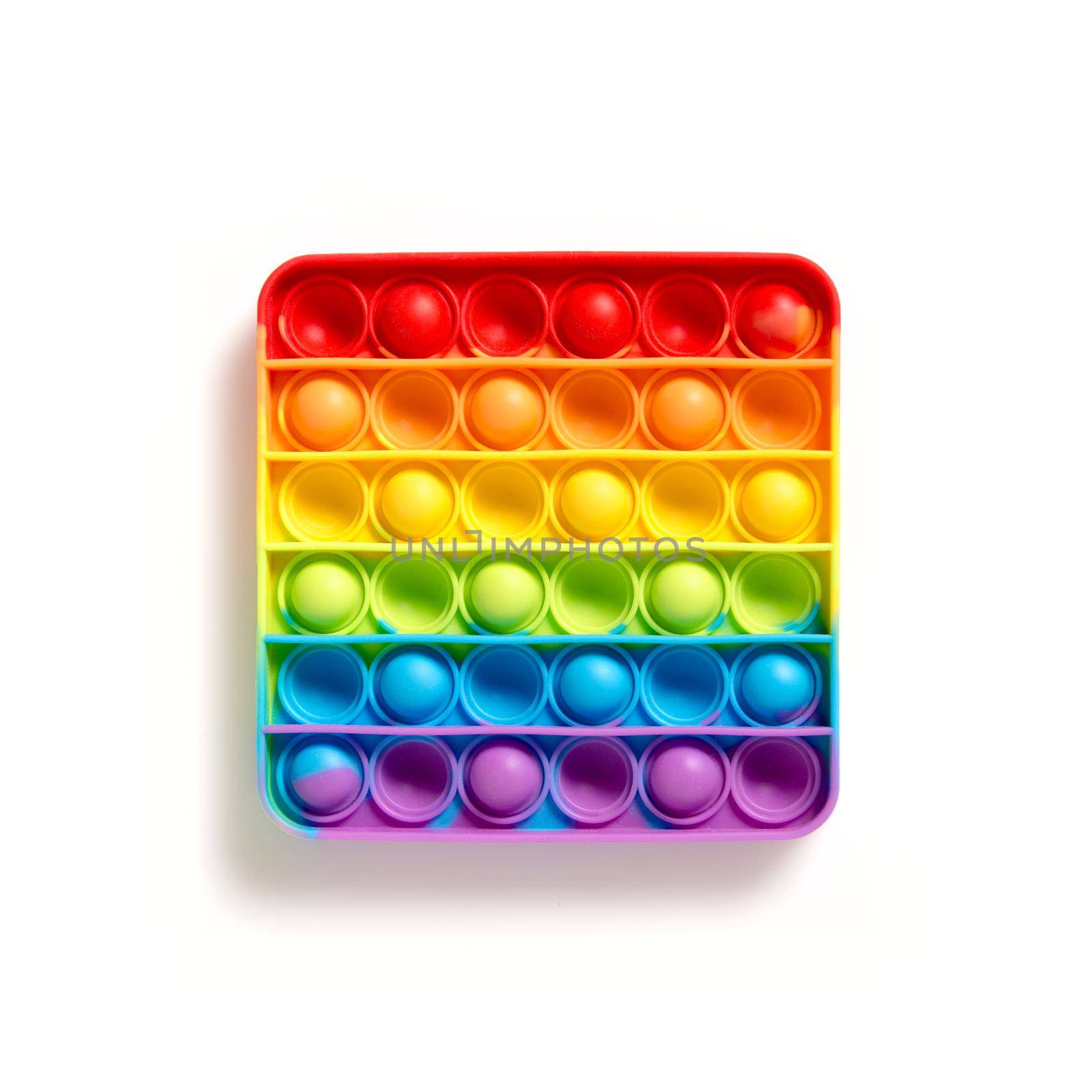 Antistress rainbow pop it fidget on white background. Simple dimple sensory game for child, development of the motor skills for hands and fingers. Popit silicone isolated on white empty copy space.