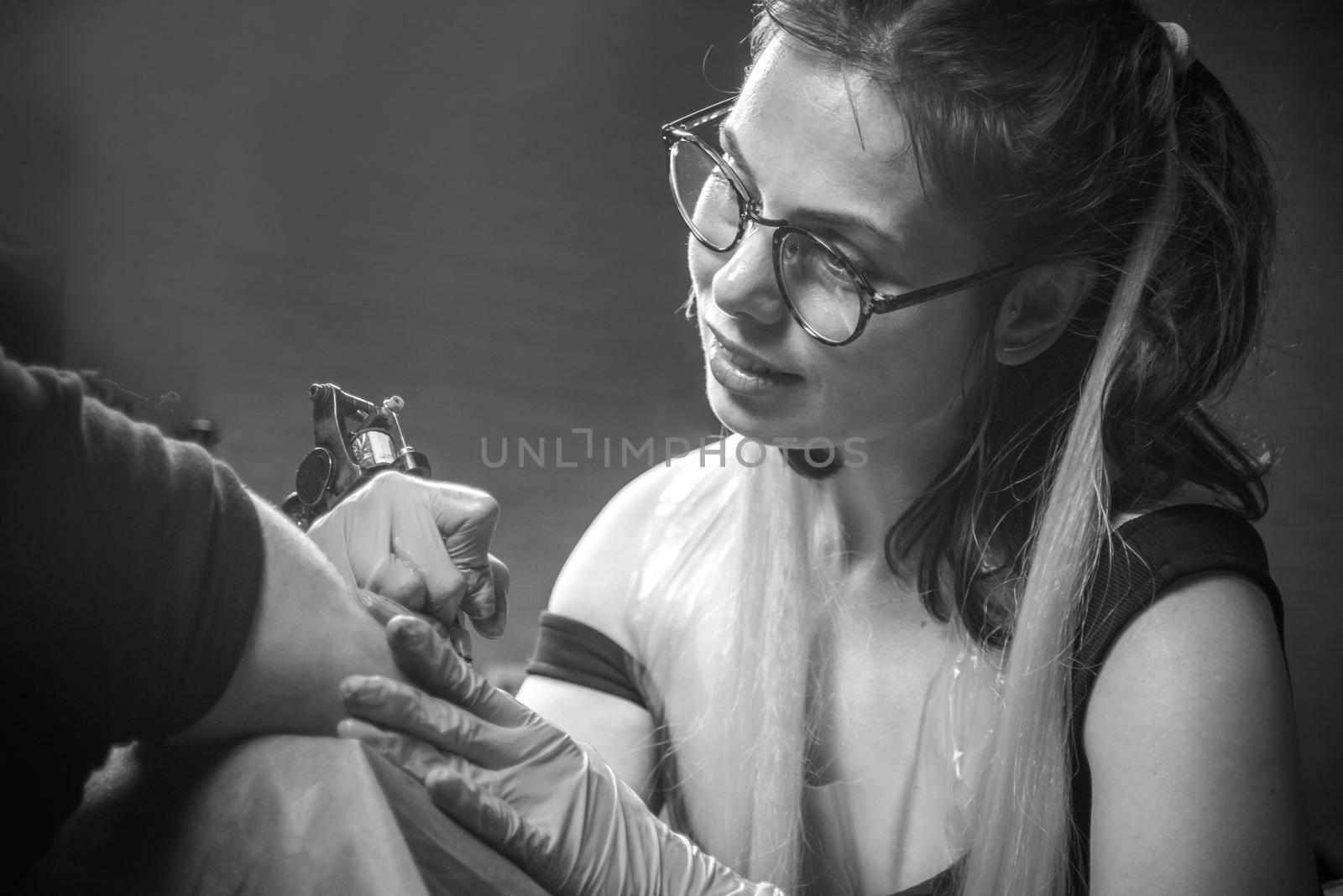 Tattoo artist demonstrates the process of getting tattoo in salon.