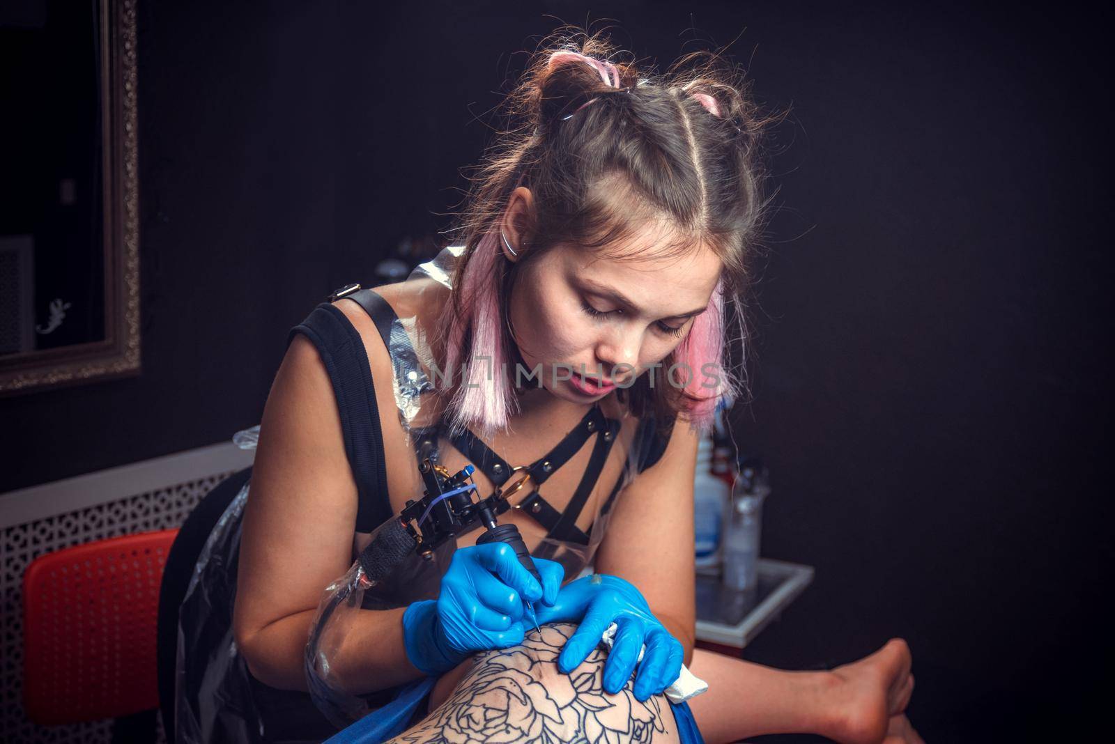 Professional tattoo artist makes tattoo in tattoo parlour./Professional tattooer doing tattoo in a workshop studio.