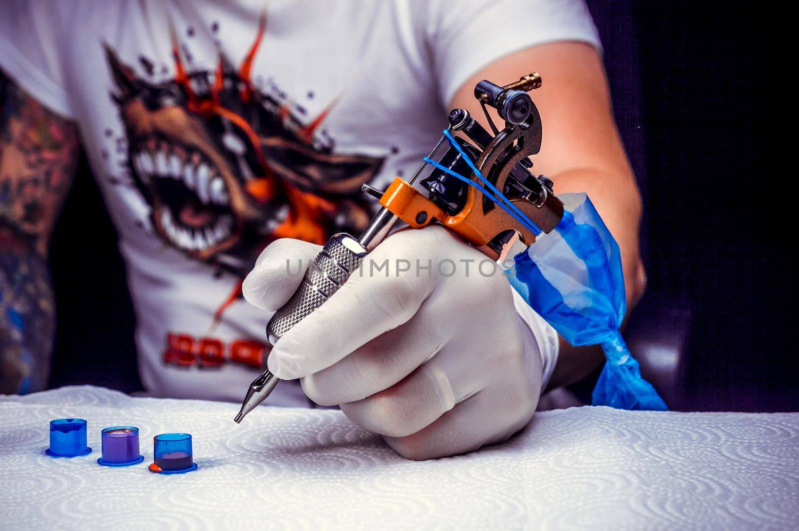 Hand of a tattoo artist with a tattoo machine.