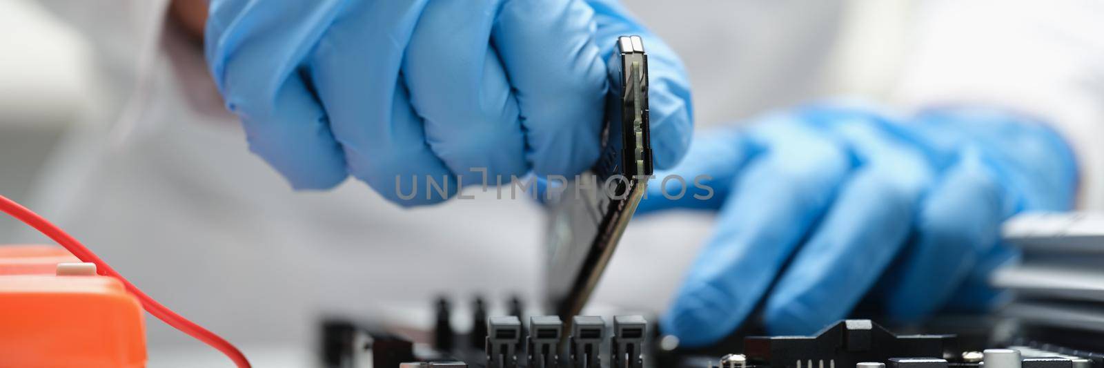 A man in production inserts a microcircuit into a device, close-up. Microchip industry, semiconductor shortage during a pandemic