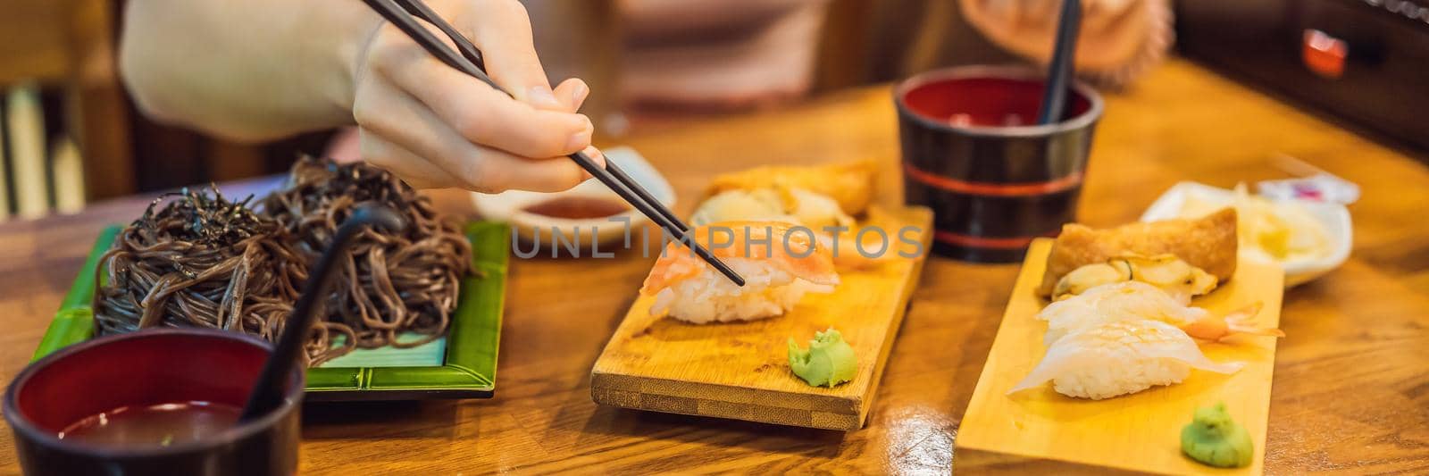 Young woman eating sushi in a cafe BANNER, LONG FORMAT by galitskaya