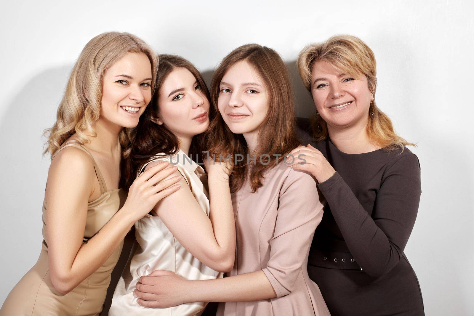 Happy Family of Mother with Three Daughters on Light Grey Background. Fashion Style Studio Portrait. Beautiful Women wearring Femininity Beige Dresses. Mothers Day, Womens Day or March 8 Style