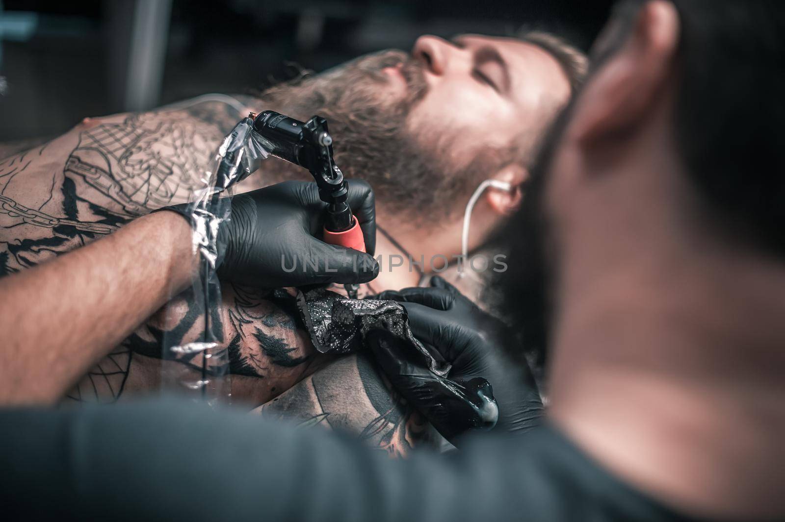 Professional tattoo artist creating a tattoo on his client salon.
