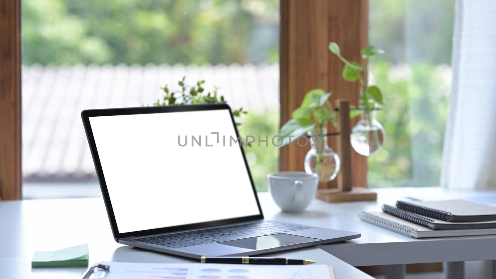 Home office desk with laptop computer, coffee cup and houseplant. by prathanchorruangsak