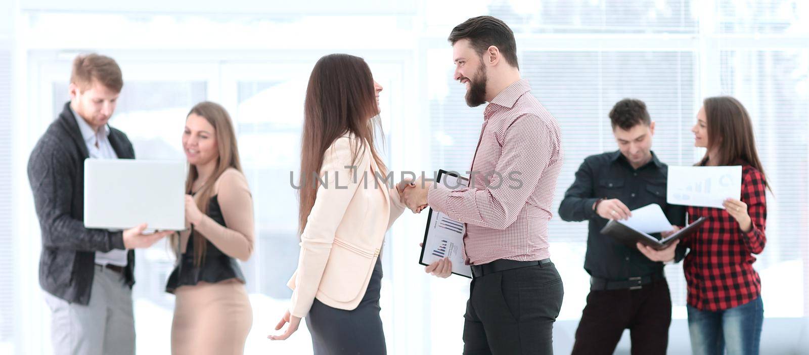 Business partners shaking hands in meeting hall by SmartPhotoLab