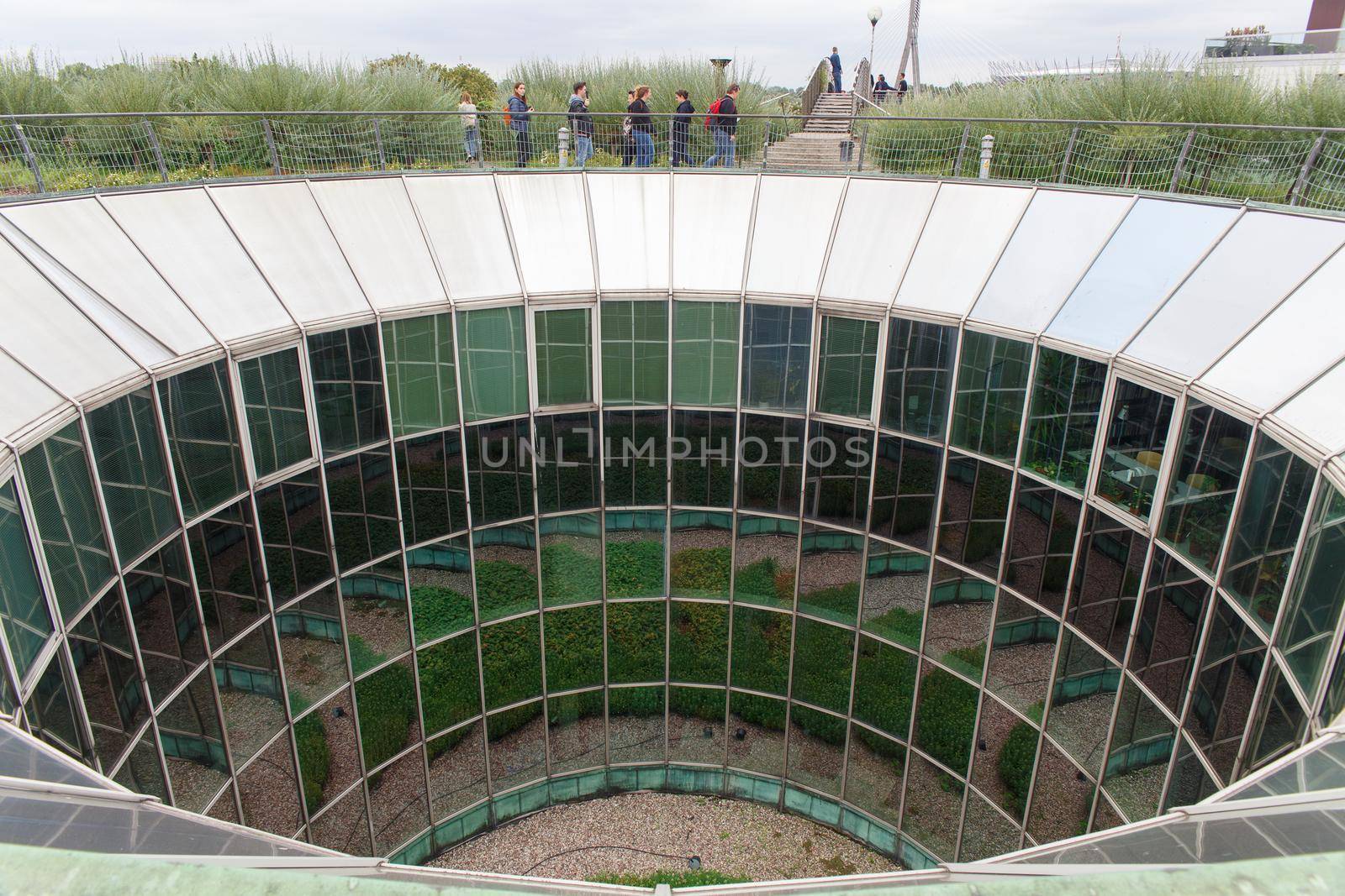 Tourists walking on roof fully glazed rounded University of Warsaw Library by BY-_-BY