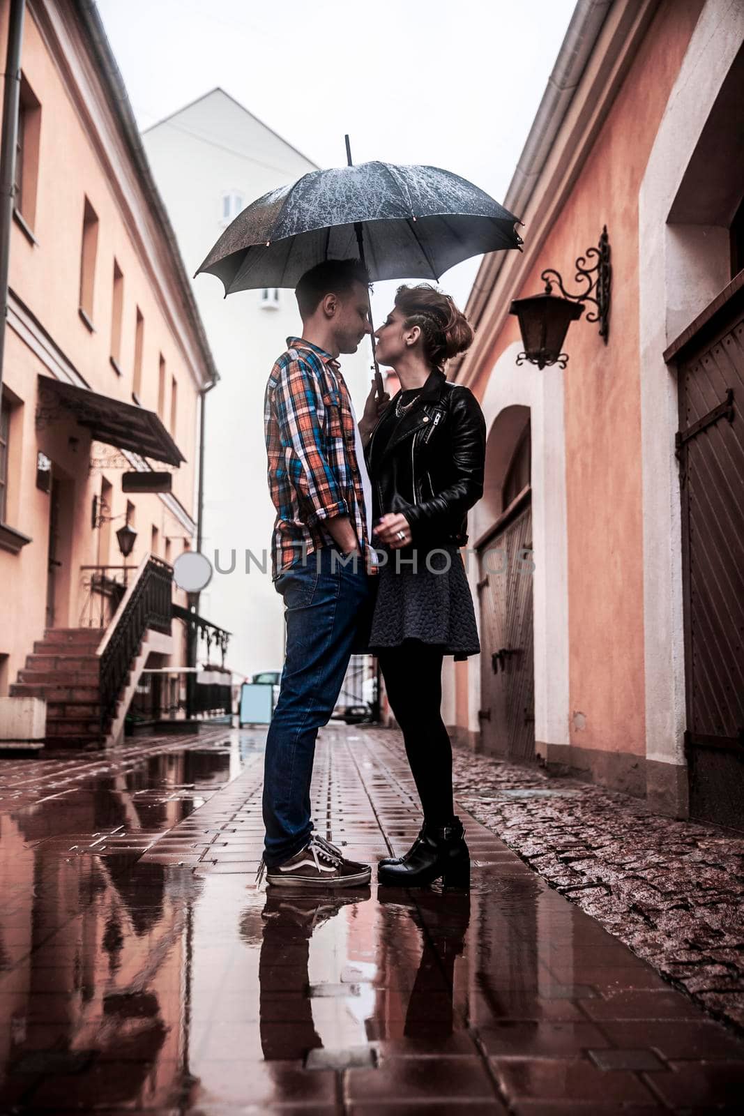 happy loving couple is under an umbrella on a city street on a rainy day by SmartPhotoLab