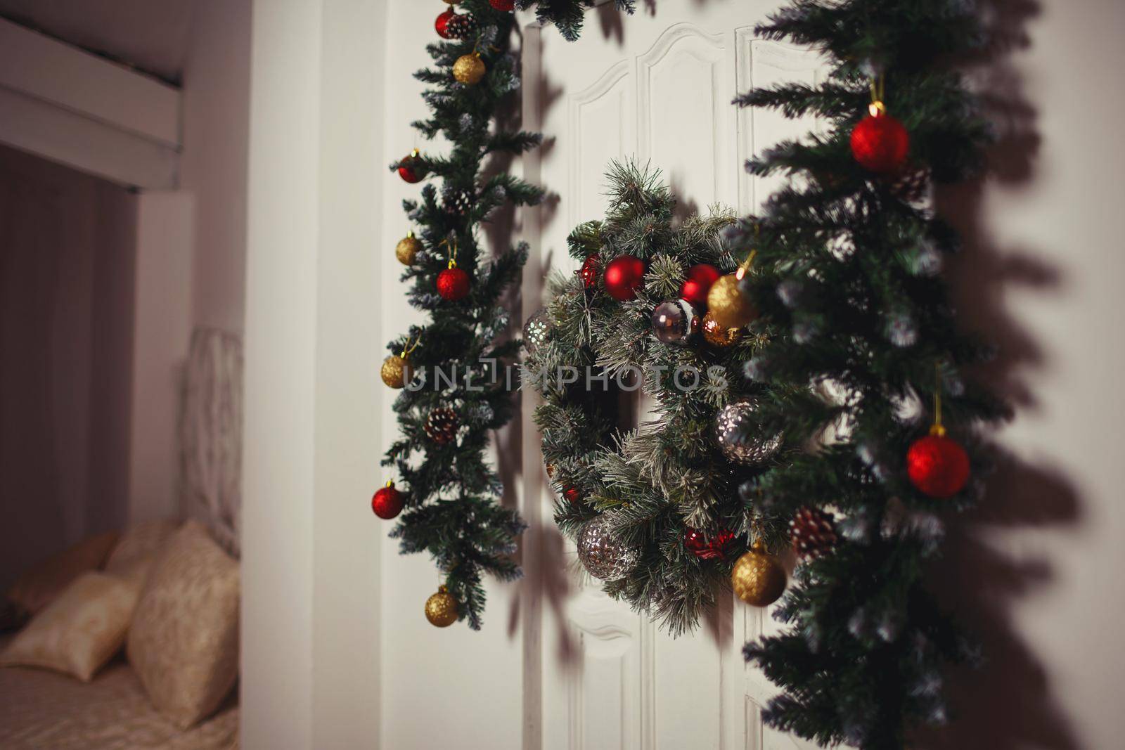 Green Christmas wreath on the white door. Christmas toys on a wreath