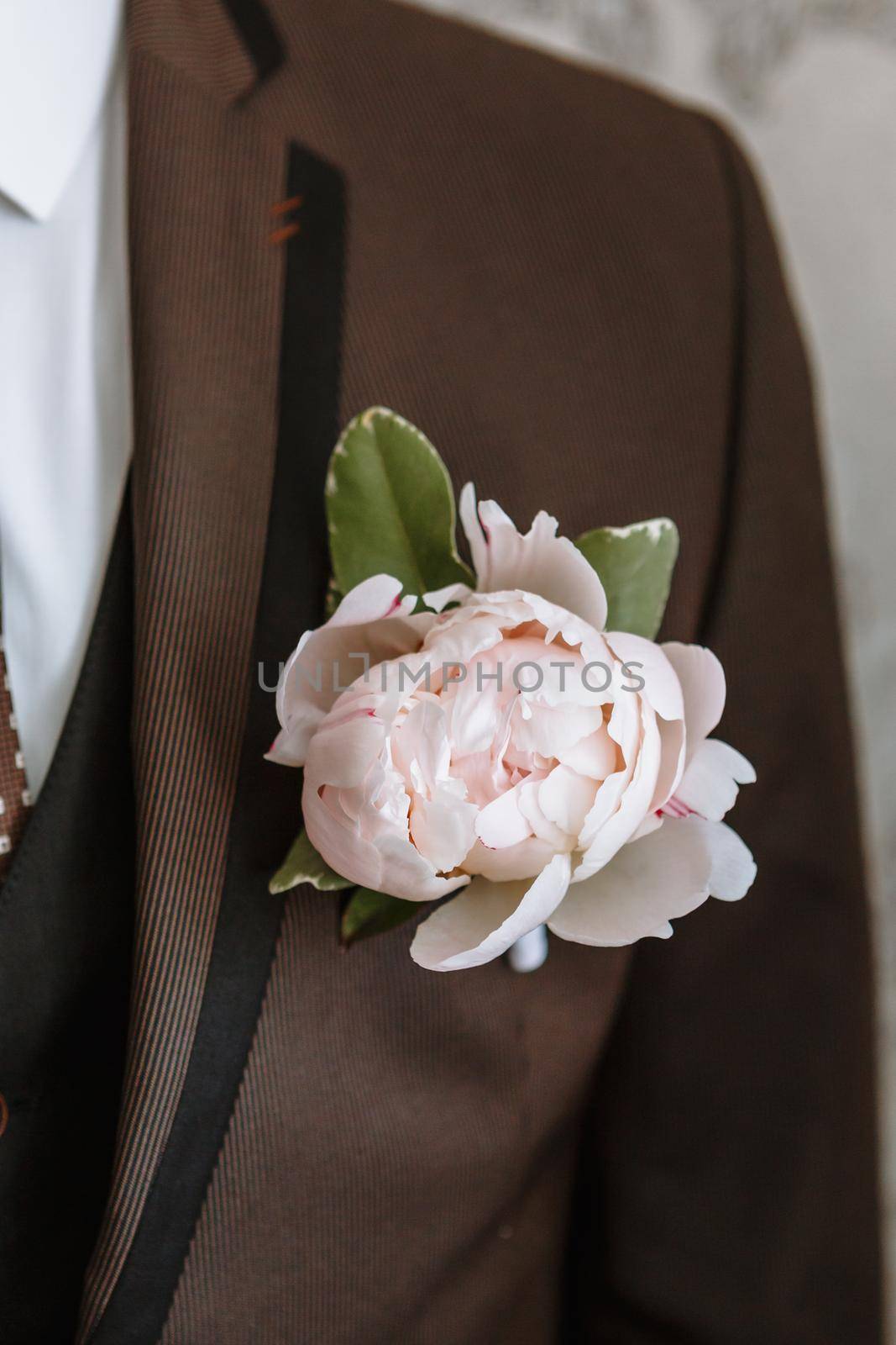 Wedding boutonniere on the groom's brown jacket