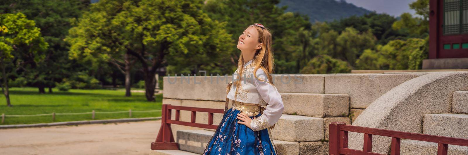 Young caucasian female tourist in hanbok national korean dress. Travel to Korea concept. National Korean clothing. Entertainment for tourists - trying on national Korean clothing. BANNER, LONG FORMAT