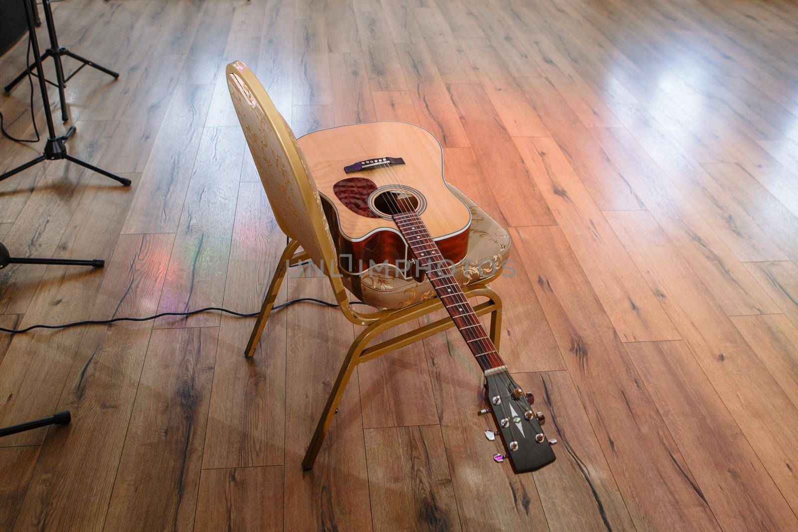 A brown six-string guitar lying on a chair.