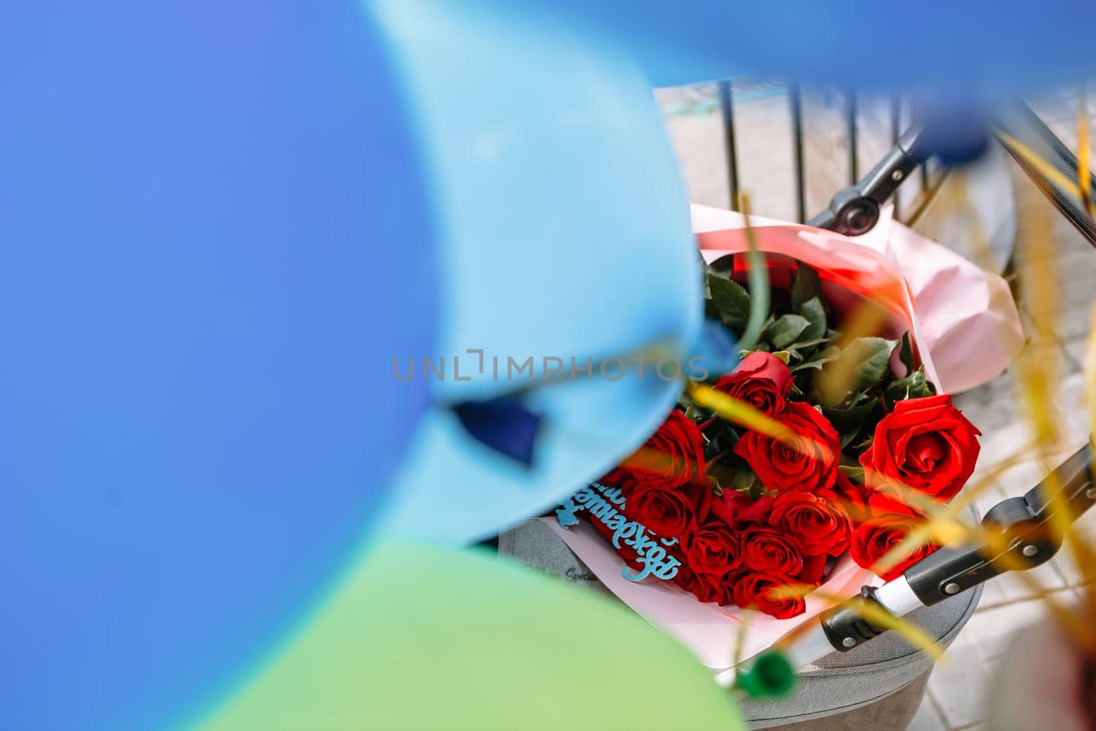 bright red roses lying in a baby carriage with balloons by deandy