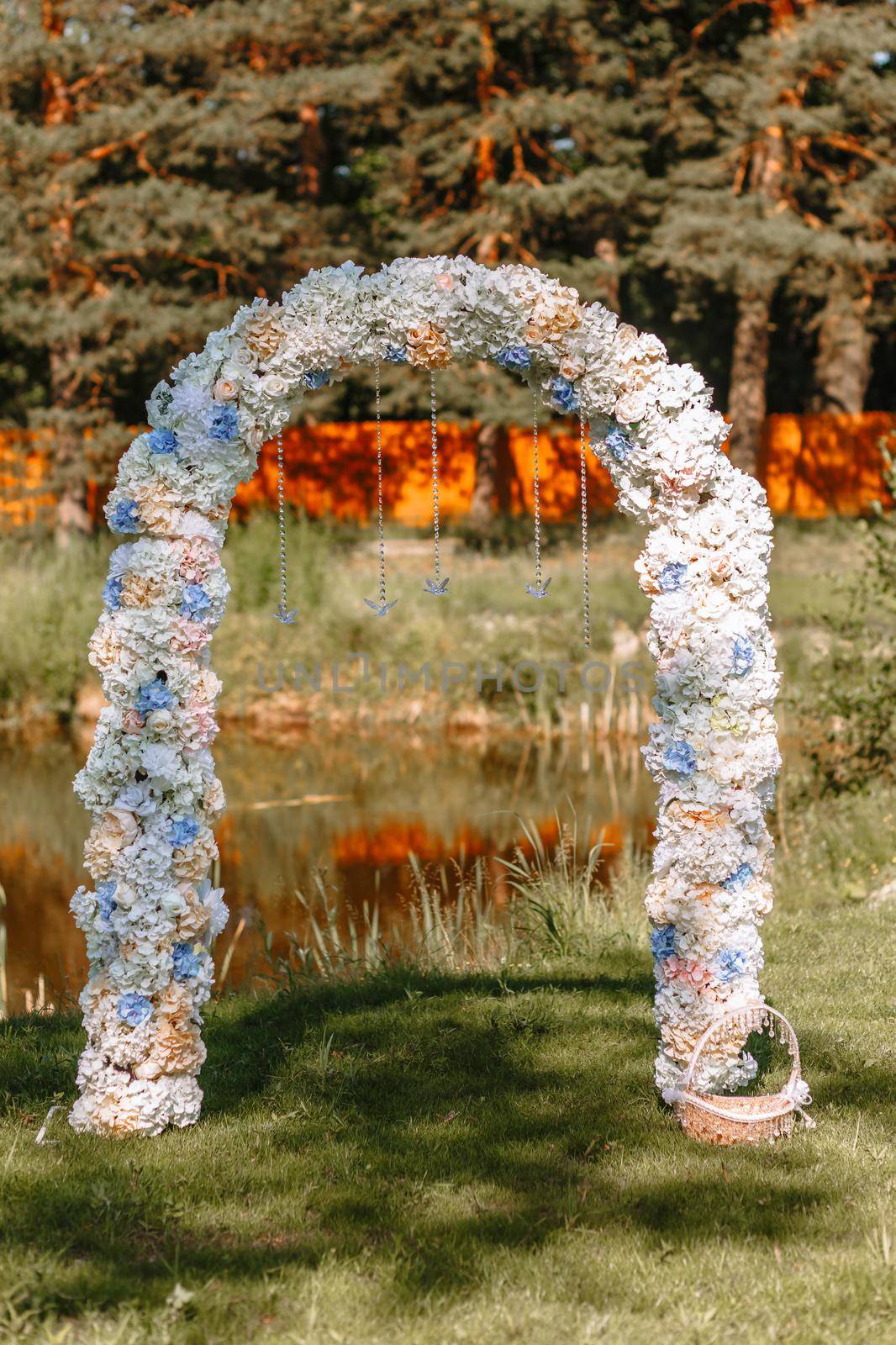 Decorative wedding arch for a photo shoot, standing on the lawn against the background of a pond