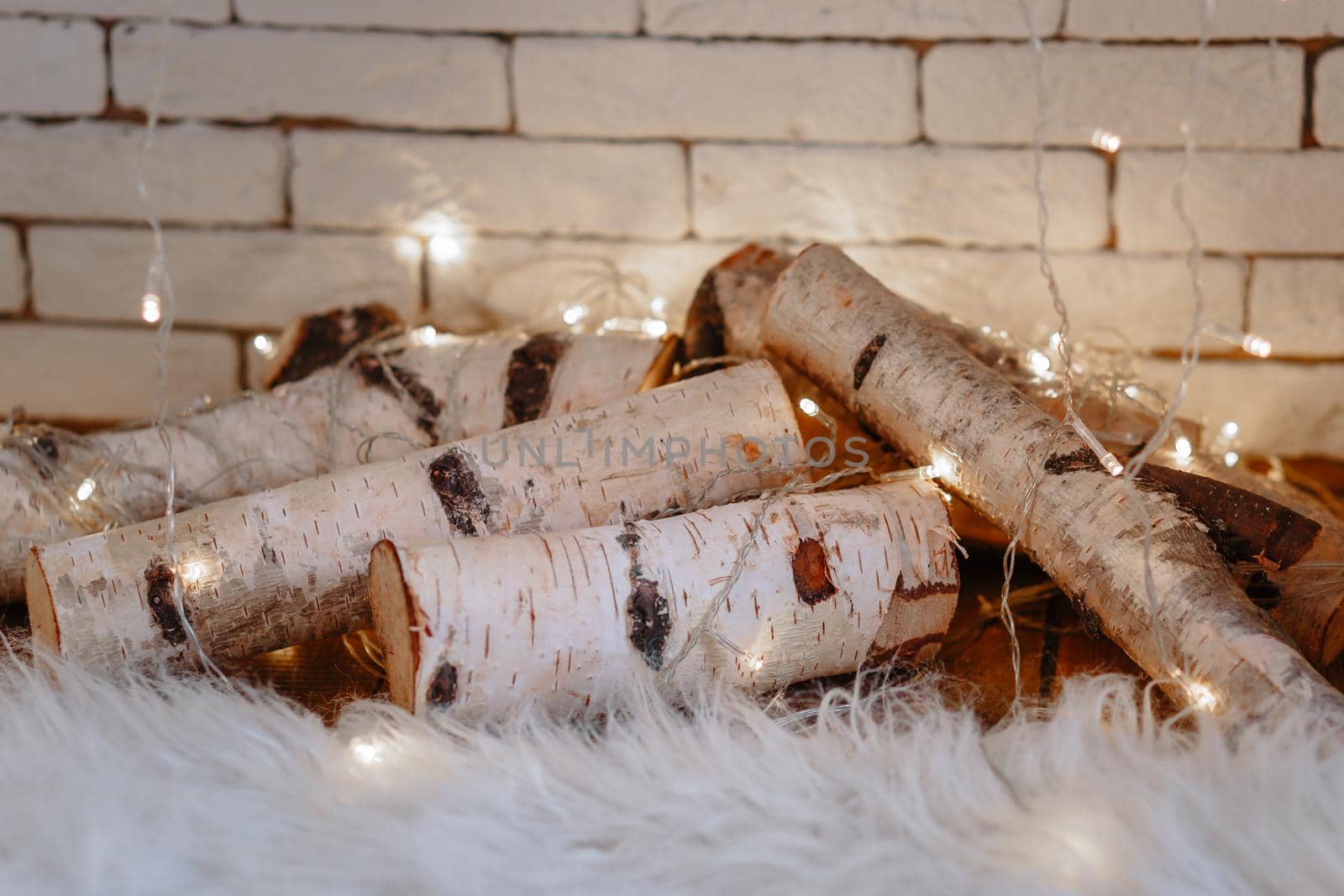 White birch logs lying in the fireplace. A garland hangs on them