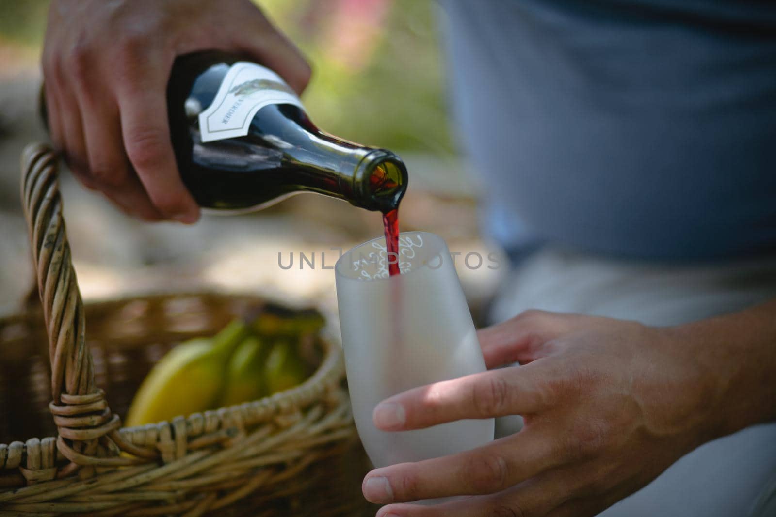 Hands of a man pouring red wine into a glass from a bottle