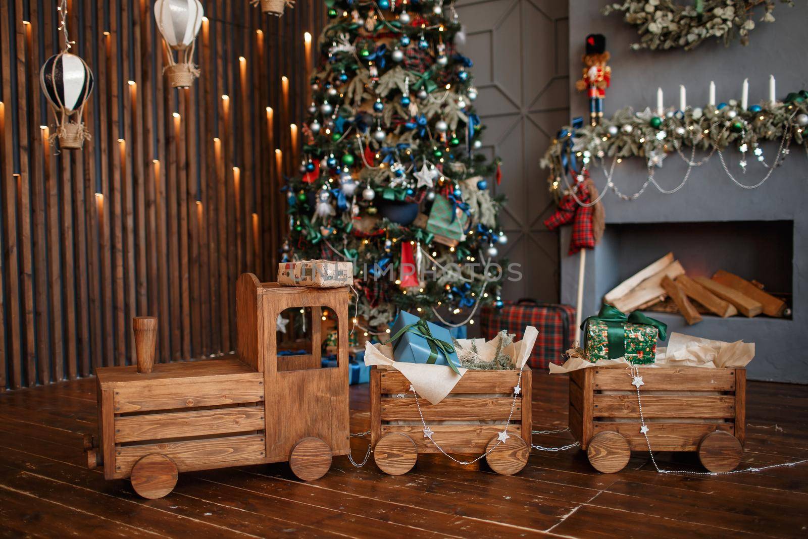 A full-length wooden steam locomotive in a Christmas photo studio.