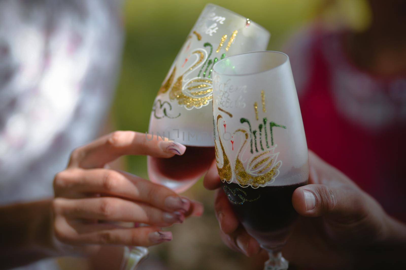Hands of a man and a woman close-up holding glasses of red wine