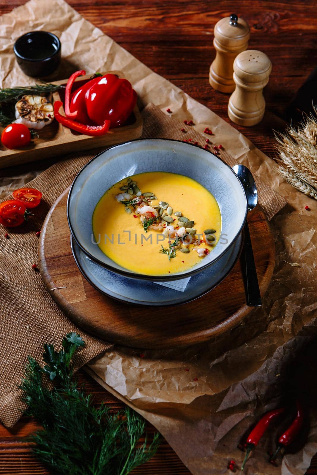 Yellow pumpkin soup in a clay plate on the table. Top view