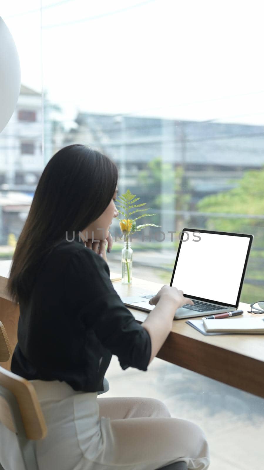 Back view of young female freelancer working online with computer laptop.