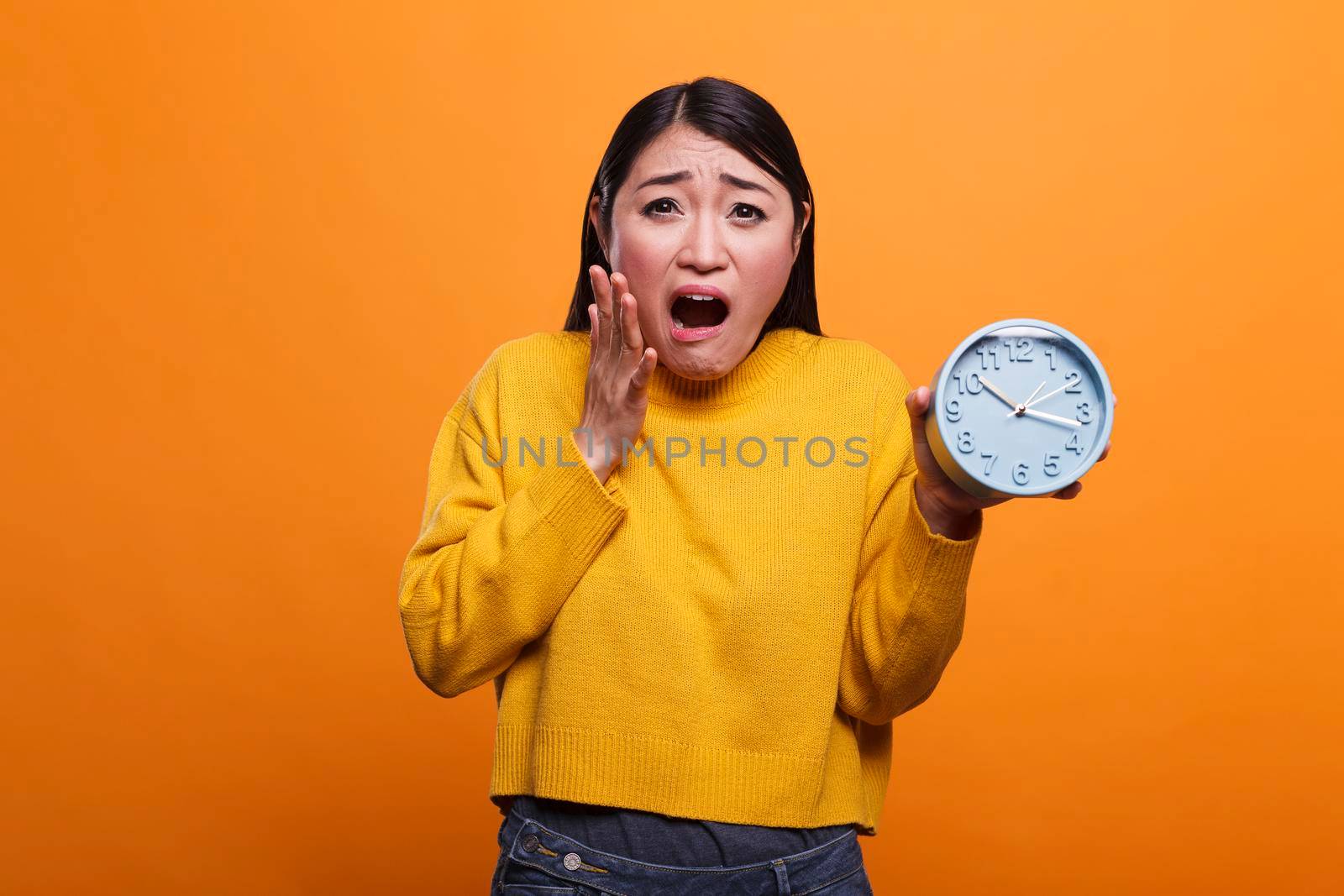 Shocked stunned lady in yellow sweater afraid because is late for work because she overslept. Speechless worried nervous asian woman in a hurry to dentist because she almost missed appointment