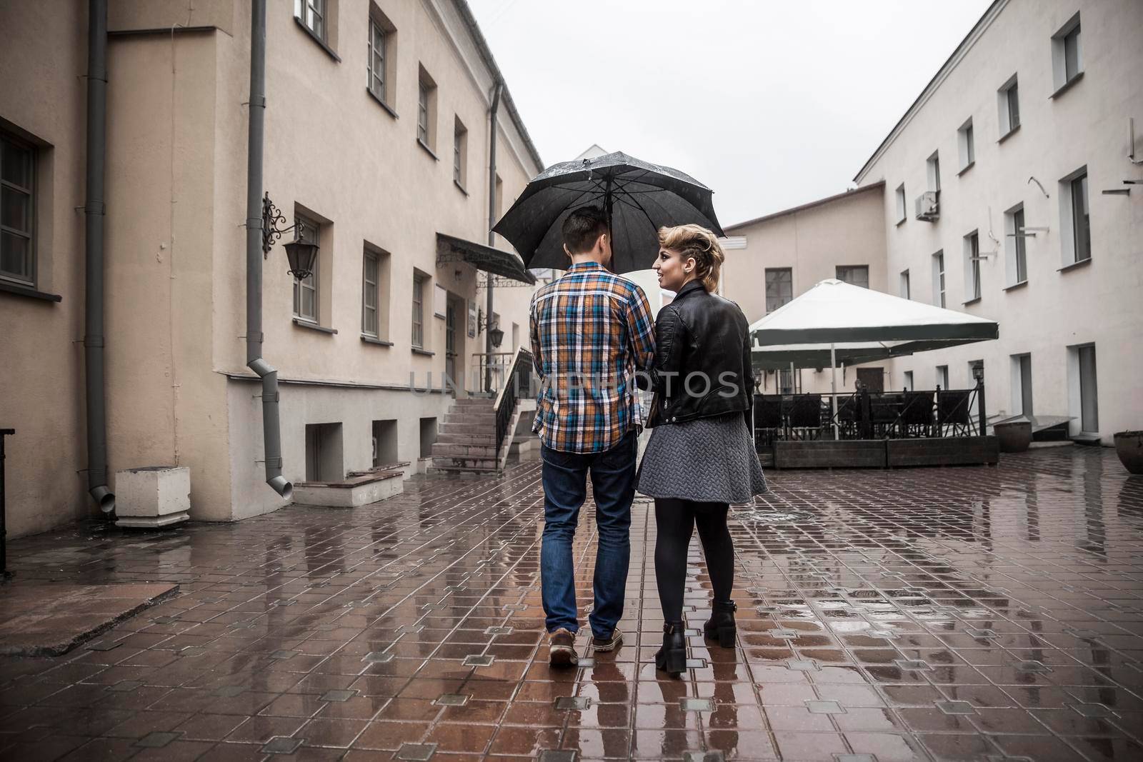 happy loving couple is under an umbrella on a city street on a rainy day by SmartPhotoLab
