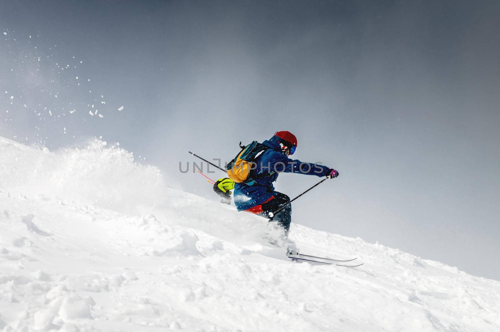 Skiing, skier, frisky - freeride, a man is stylishly skiing on a snowy slope with snow dust plume behind him.