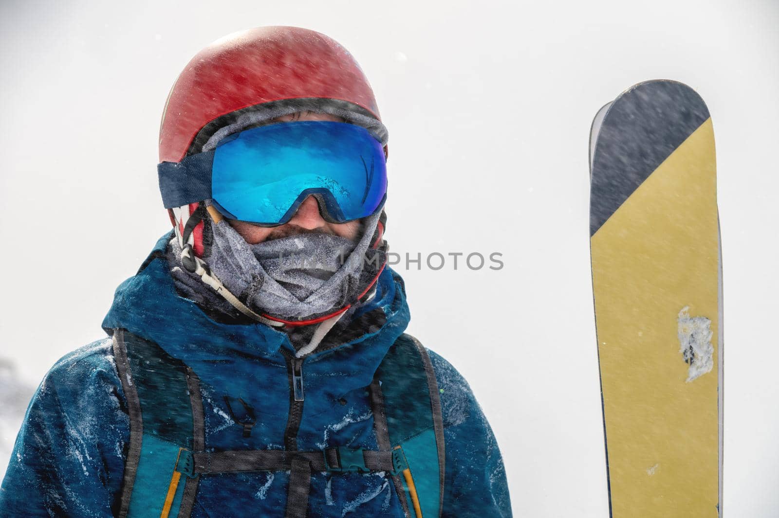 Closeup portrait of ski goggles of a man with reflection of snowy mountains. The mountain range is reflected in the ski mask. Portrait of a man in a ski resort against the backdrop of mountains and sky in a snow blizzard.