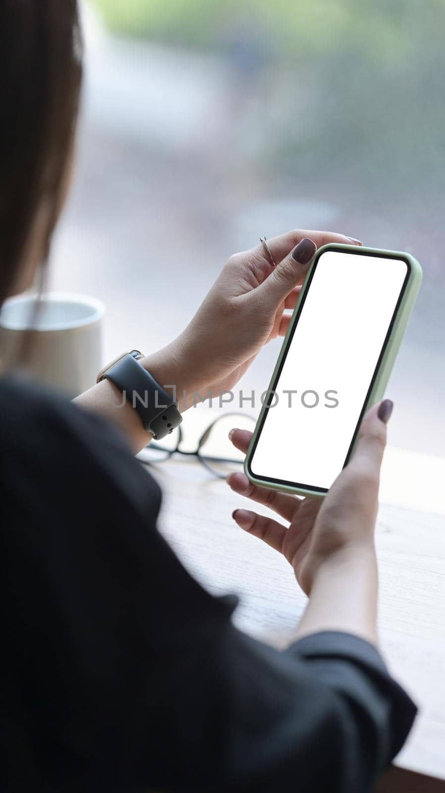 Young woman using smartphone at bright office. Blank screen for graphics display montage.