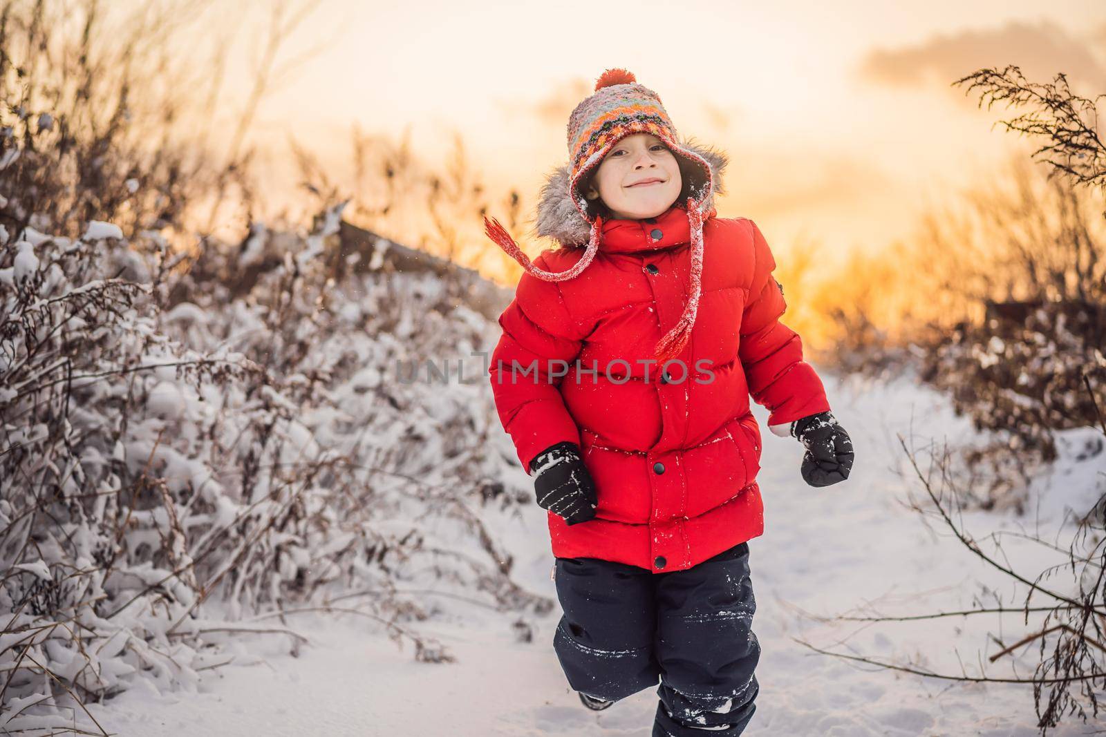 Cute boy in red winter clothes runs fun in the snow. Winter Fun Outdoor Concepts by galitskaya