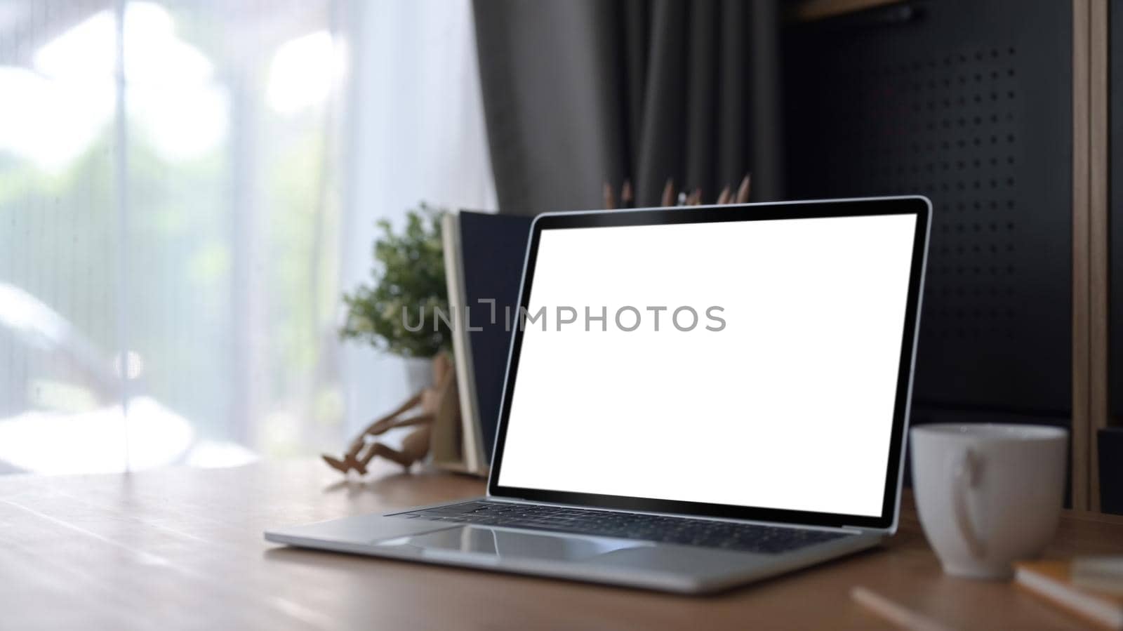 Computer laptop with empty screen, coffee cup and book on wooden table, Comfortable workplace. by prathanchorruangsak